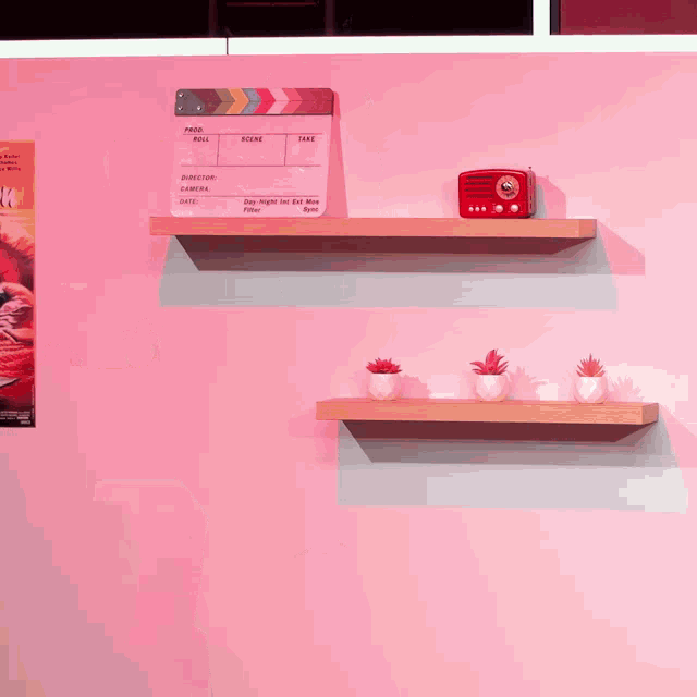 a pink wall with shelves and a clapper board that says take