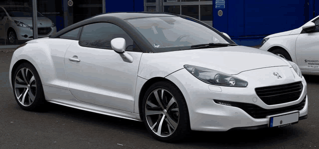 a white sports car is parked in front of a blue building