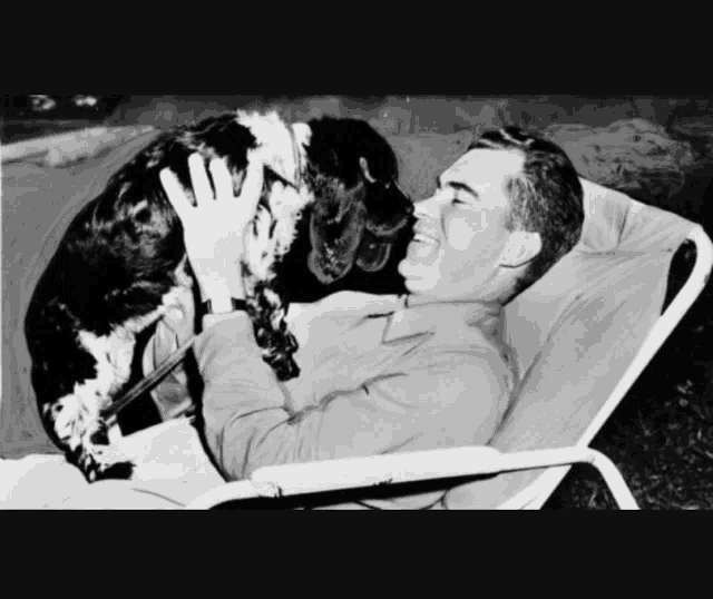 a black and white photo of a man petting his dog