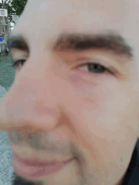 a close up of a man 's face with a blurry background and a sign that says ' a ' on it