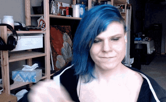 a woman with blue hair is standing in front of a shelf with a no smoking sign on it
