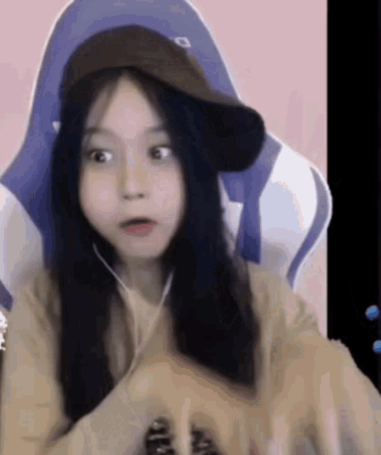 a girl wearing a hat is sitting in a gaming chair