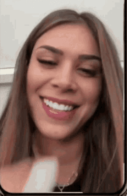 a woman is smiling on a cell phone screen