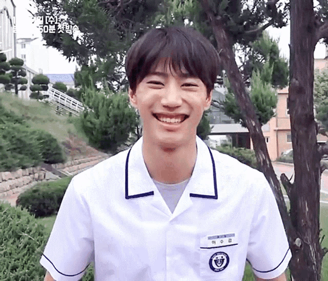 a young man in a school uniform is smiling and wearing a name tag that says ' 이수경 ' on it