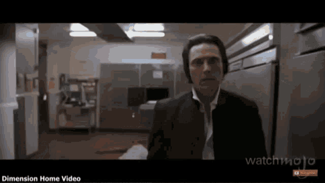 a man in a black suit is standing in a room with the words dimension home video on the bottom