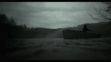 a man is rowing a boat in a dark lake .