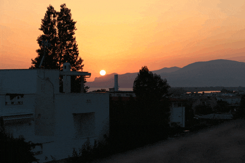 a sunset with a building in the foreground and a satellite dish on top of it