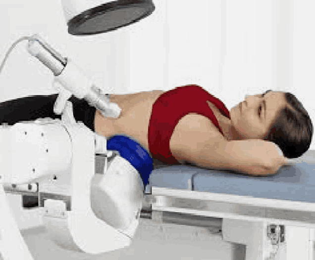 a woman is laying on a table with a machine on her stomach and getting a treatment .