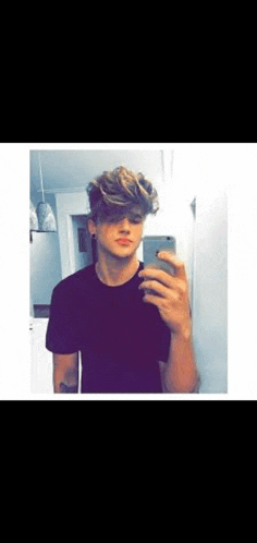 a young man is taking a selfie in a mirror with his phone .