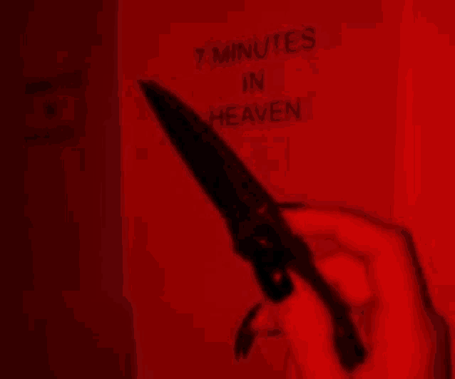 a woman is holding a knife in her hand in front of a red wall .