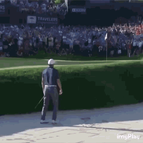 a man is standing on a golf course with a crowd behind him and a sign that says travelers on it