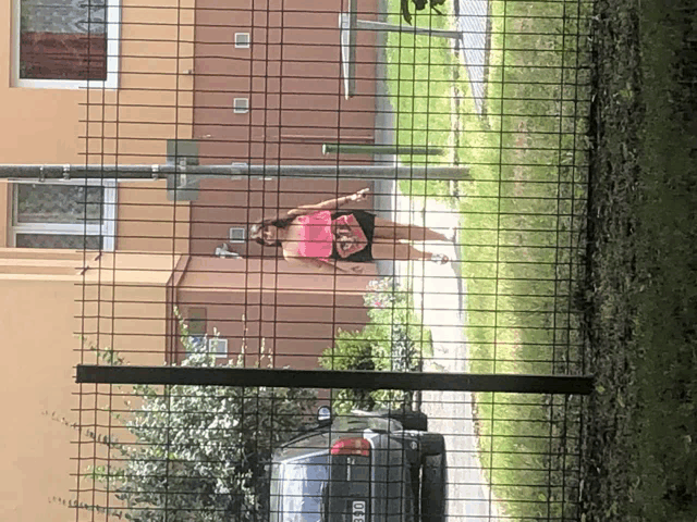 a woman wearing a pink shirt that says ' i love you ' on it walks behind a fence