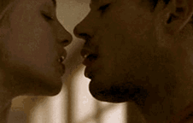 a man and a woman are kissing each other in a dark room .