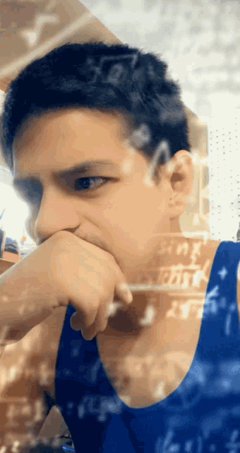 a young man in a blue tank top is looking at the camera