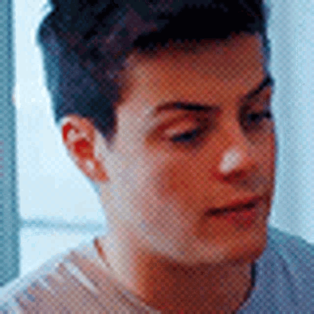 a close up of a young man 's face with a gray shirt on .