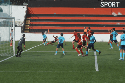 a group of soccer players are playing on a field with a sign that says sport in the background