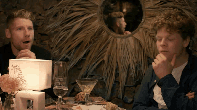 two men sitting at a table with a martini glass