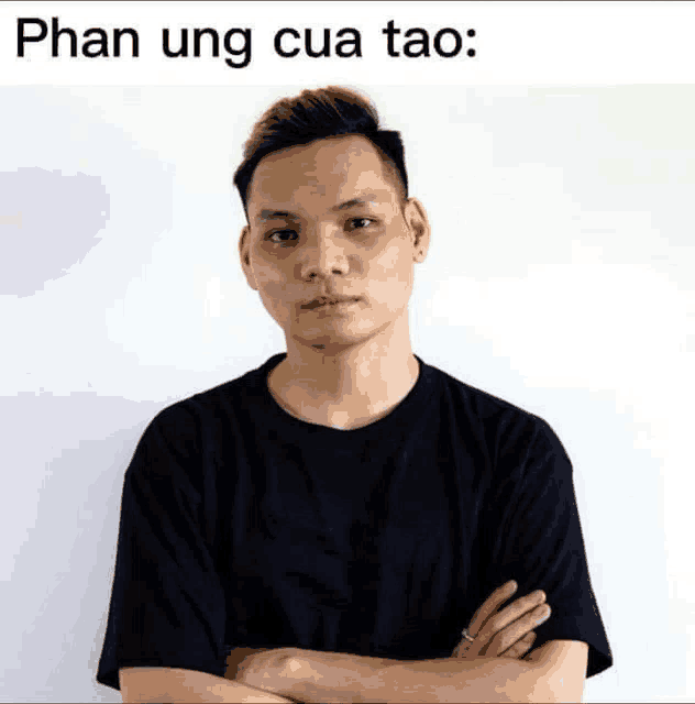 a man stands with his arms crossed in front of a white wall with the words phan ung cua tao written above him