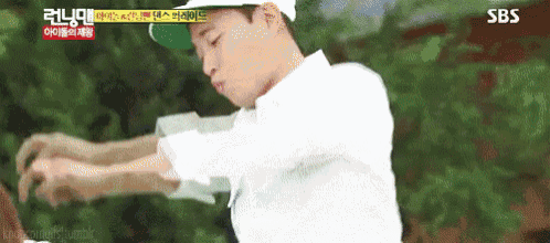 a man wearing a white shirt and a green hat is standing in front of a sbs logo .