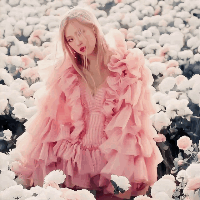 a woman in a pink dress stands in a field of flowers