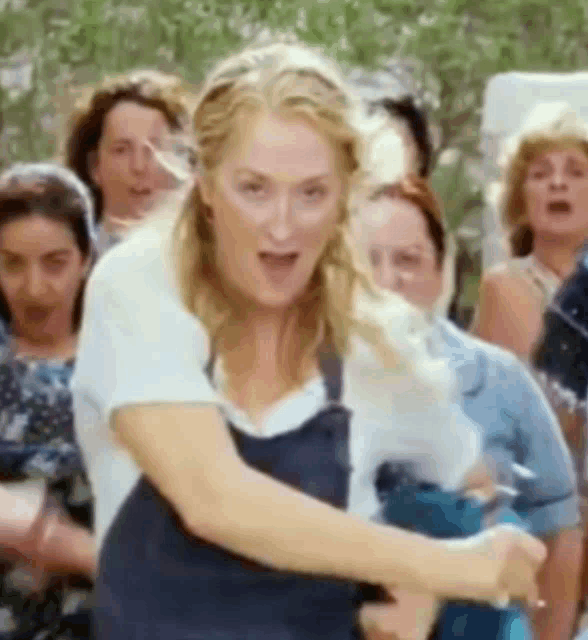 a woman is standing in front of a crowd of people holding a bottle of water .