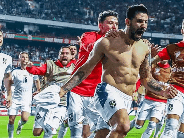 a shirtless soccer player is surrounded by his teammates including number 15