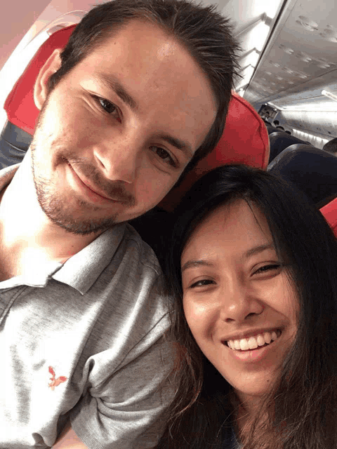 a man and a woman are posing for a picture on an airplane seat