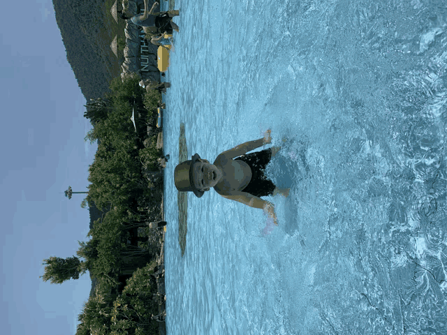 a boy in a hat is swimming in a pool with a sign that says nutt on it