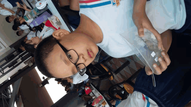 a boy wearing glasses is holding a plastic container with a label that says ' a ' on it