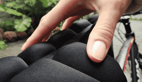 a close up of a person 's hand touching a cushion with a bicycle in the background