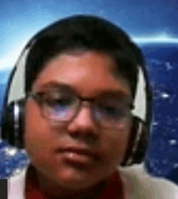 a boy wearing headphones and glasses is looking at the camera .