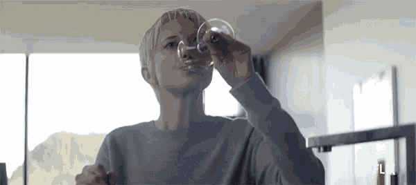 a woman is drinking a glass of water from a glass .