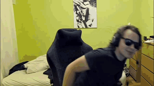 a man wearing sunglasses and headphones is sitting in a chair in a bedroom .