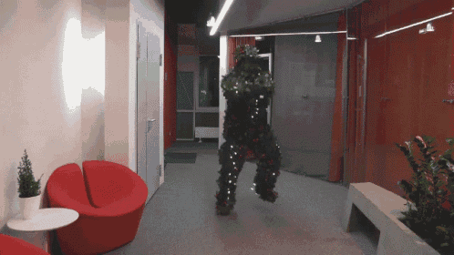 a person dressed as a christmas tree is in a hallway