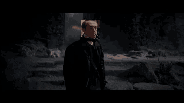 a man in a tuxedo is smoking a cigarette in a dark cave