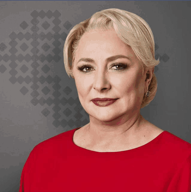 a woman in a red dress is standing in front of a gray background