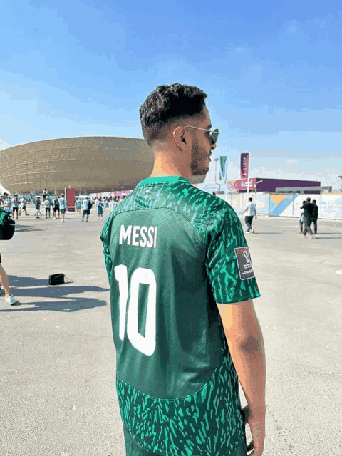 a man wearing a green shirt that says messi on the back