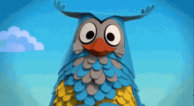 a blue and gray owl with big eyes and a red beak stands in front of a blue sky