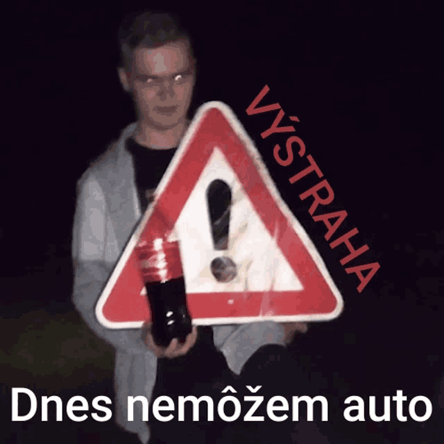 a man is holding a coca cola bottle in front of a sign that says vystraha