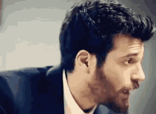 a man in a suit and tie is looking at the camera .