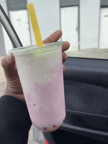 a person is holding a pink and white smoothie with a yellow straw