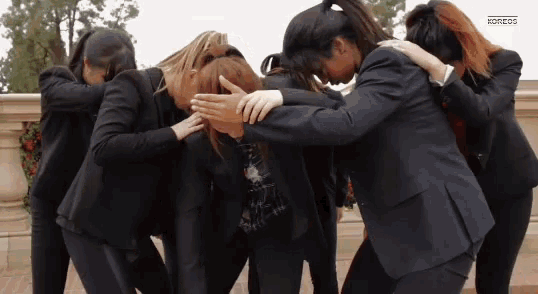 a group of women standing in a huddle with their arms around each other