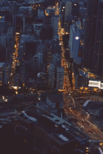 an aerial view of a city at night with a building with a purple light on the top of it