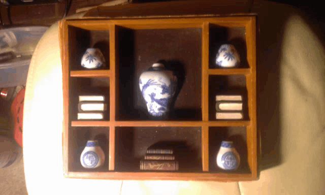 a wooden shelf with a blue and white vase in the center