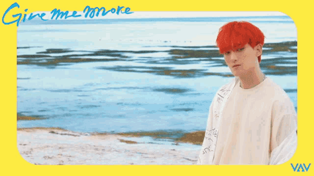 a man with red hair is standing on a beach with the words give me more written on the bottom