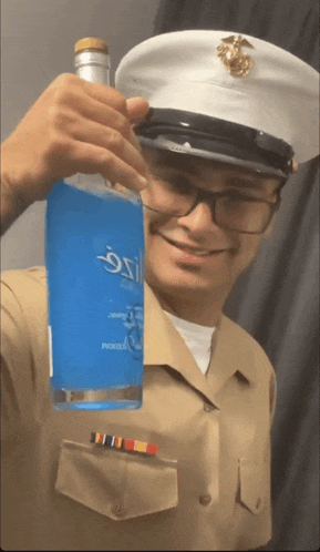 a man in a military uniform is holding a bottle of blue liquid that says ozzy