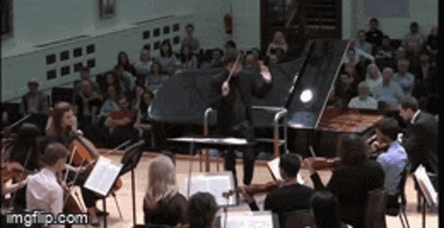 a man playing a violin in front of an orchestra and a piano ..