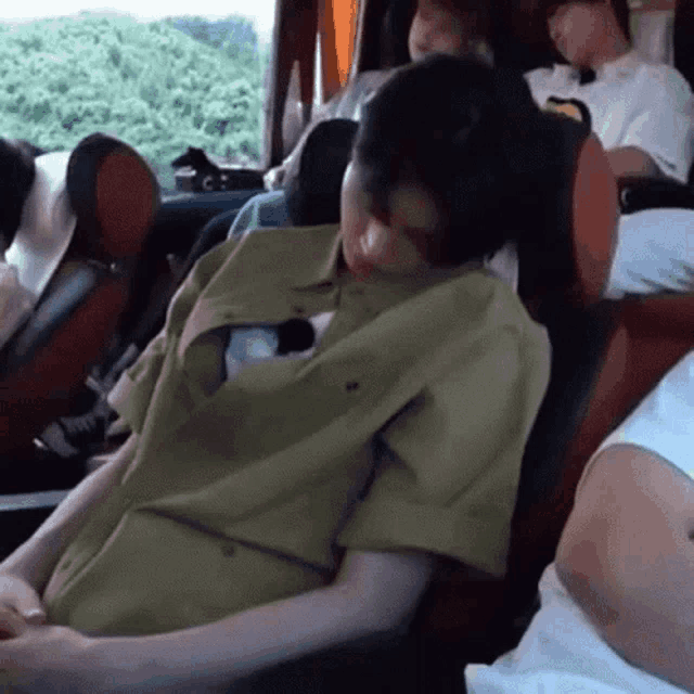 a man in a green shirt sleeping on a bus