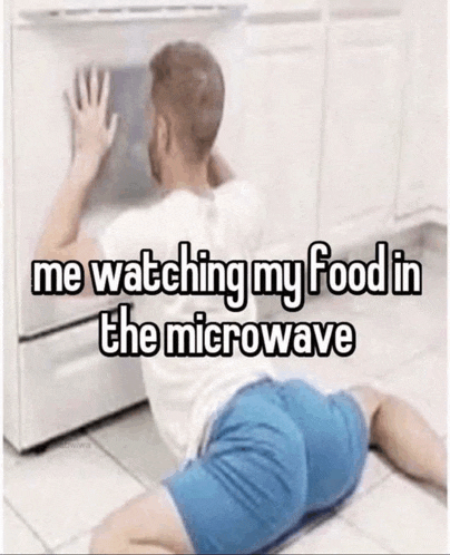 a man is laying on the floor in front of a microwave .