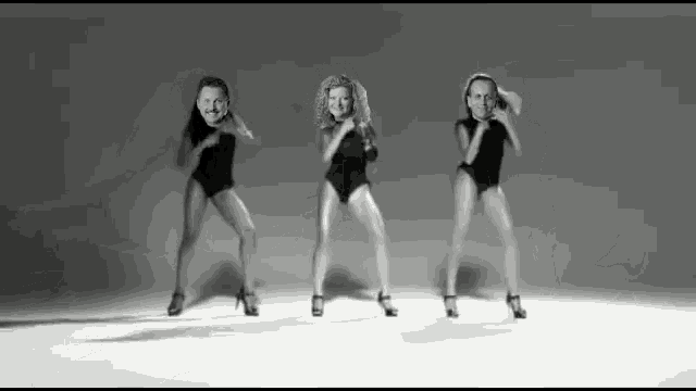 three women in black leotards are dancing in a black and white photo .